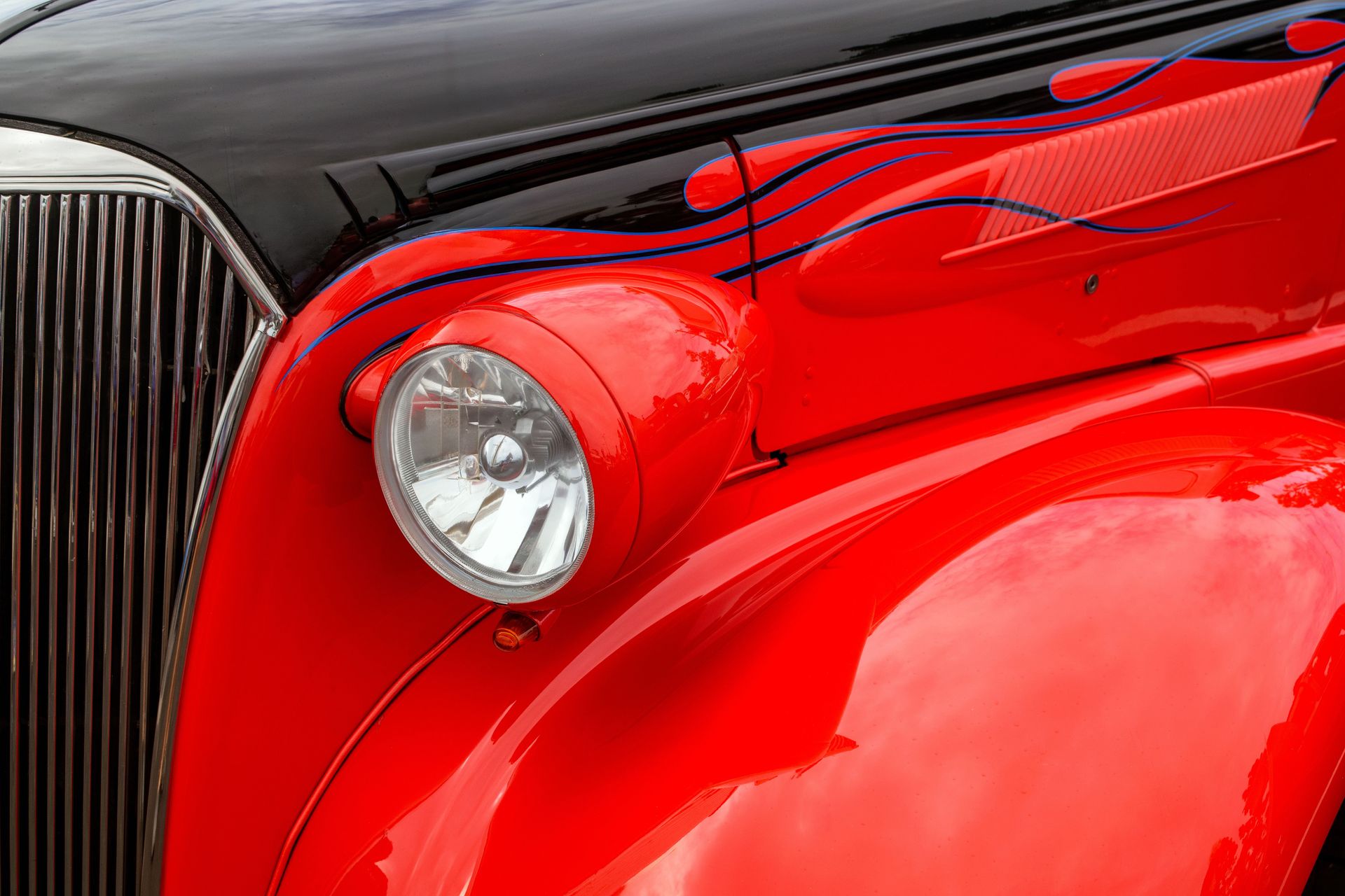 Close-up of a vintage car's vibrant red hood with custom flame detailing.