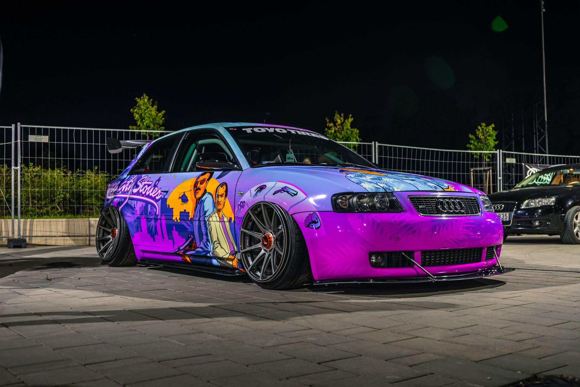 Vibrant custom Audi adorned with colorful graffiti art at night.