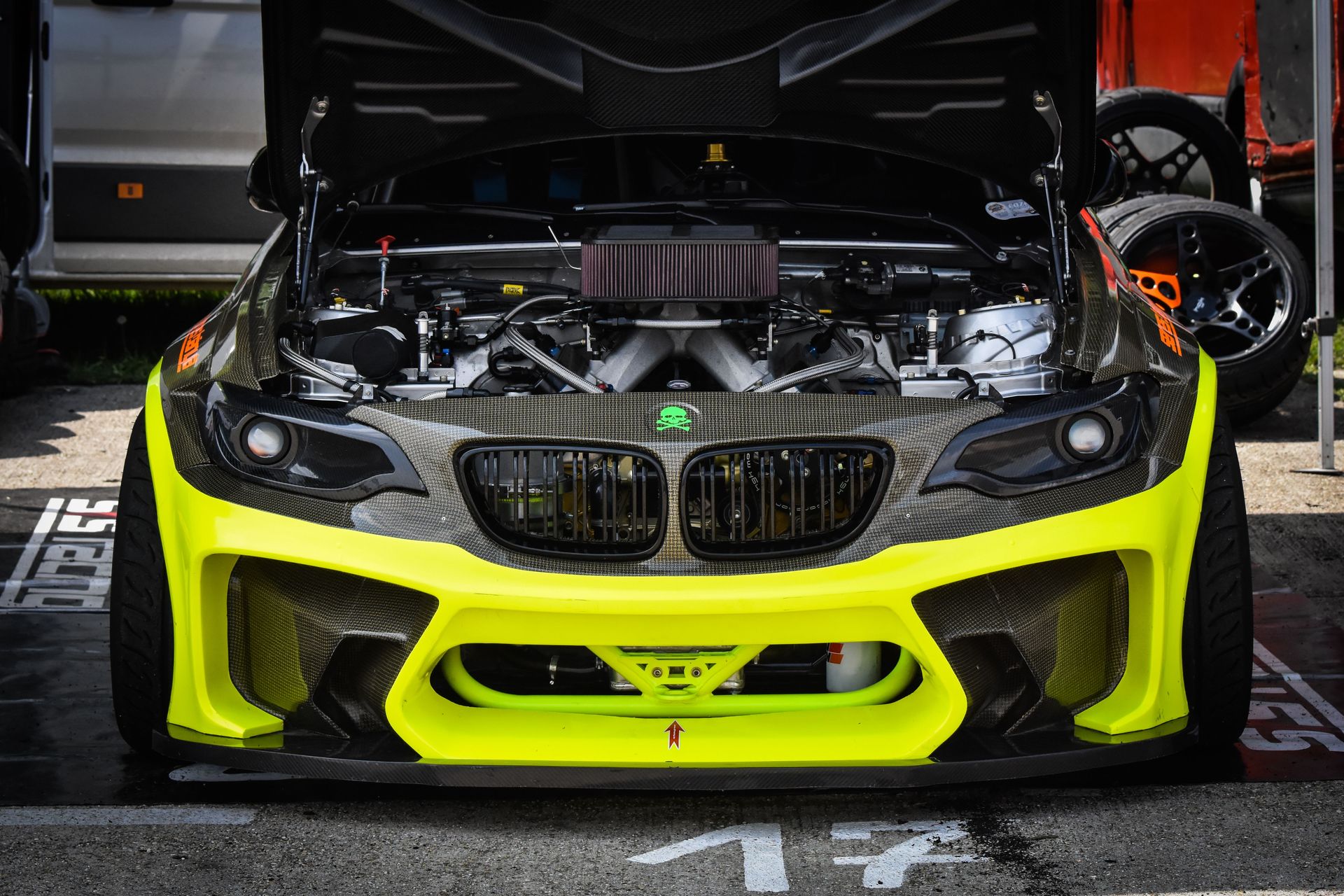 Bright yellow race car with open hood showcasing engine mechanics, highlighting performance parts.