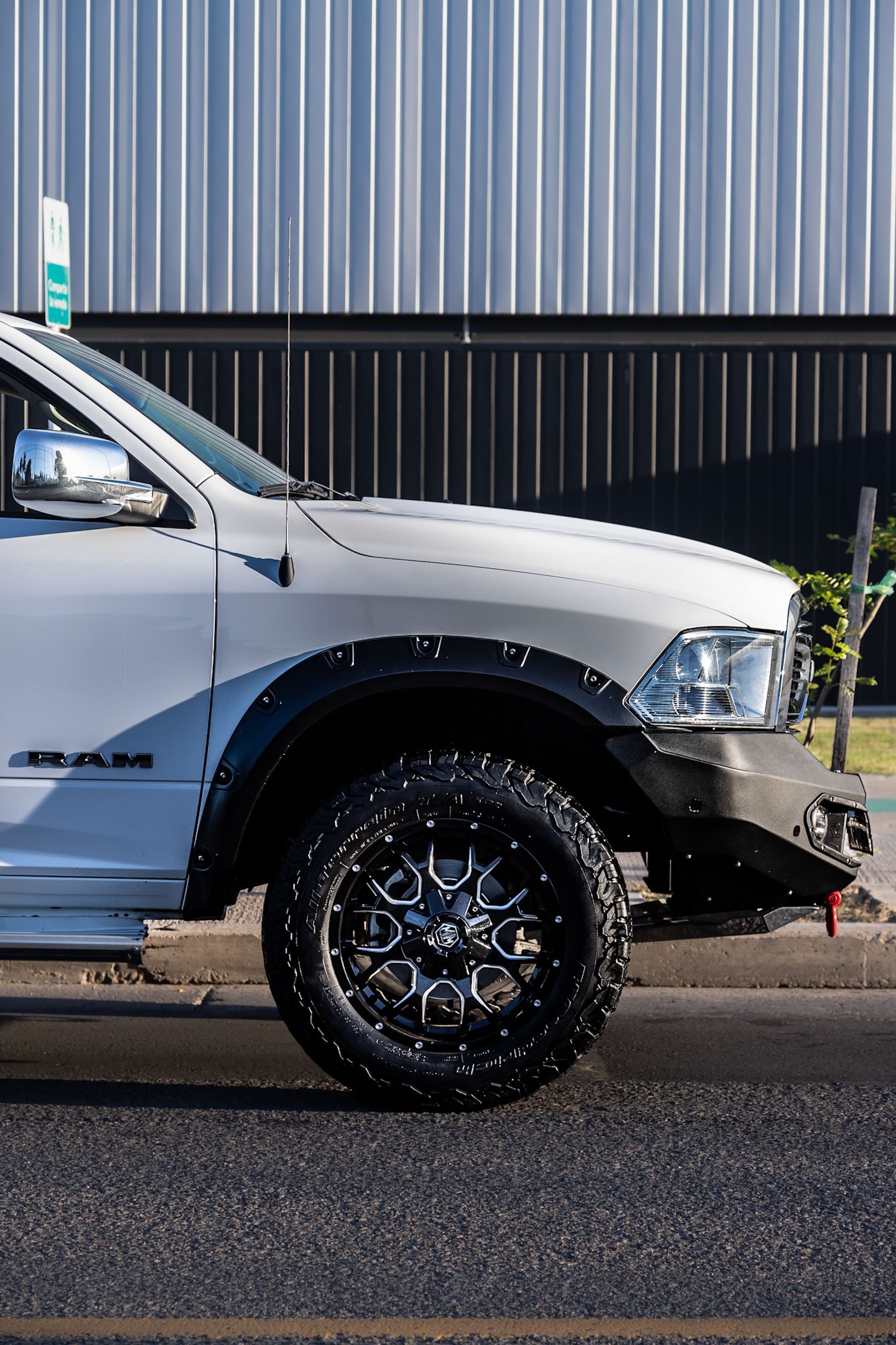Detailed side view of a white 4x4 truck showcasing custom wheel design and bumper.